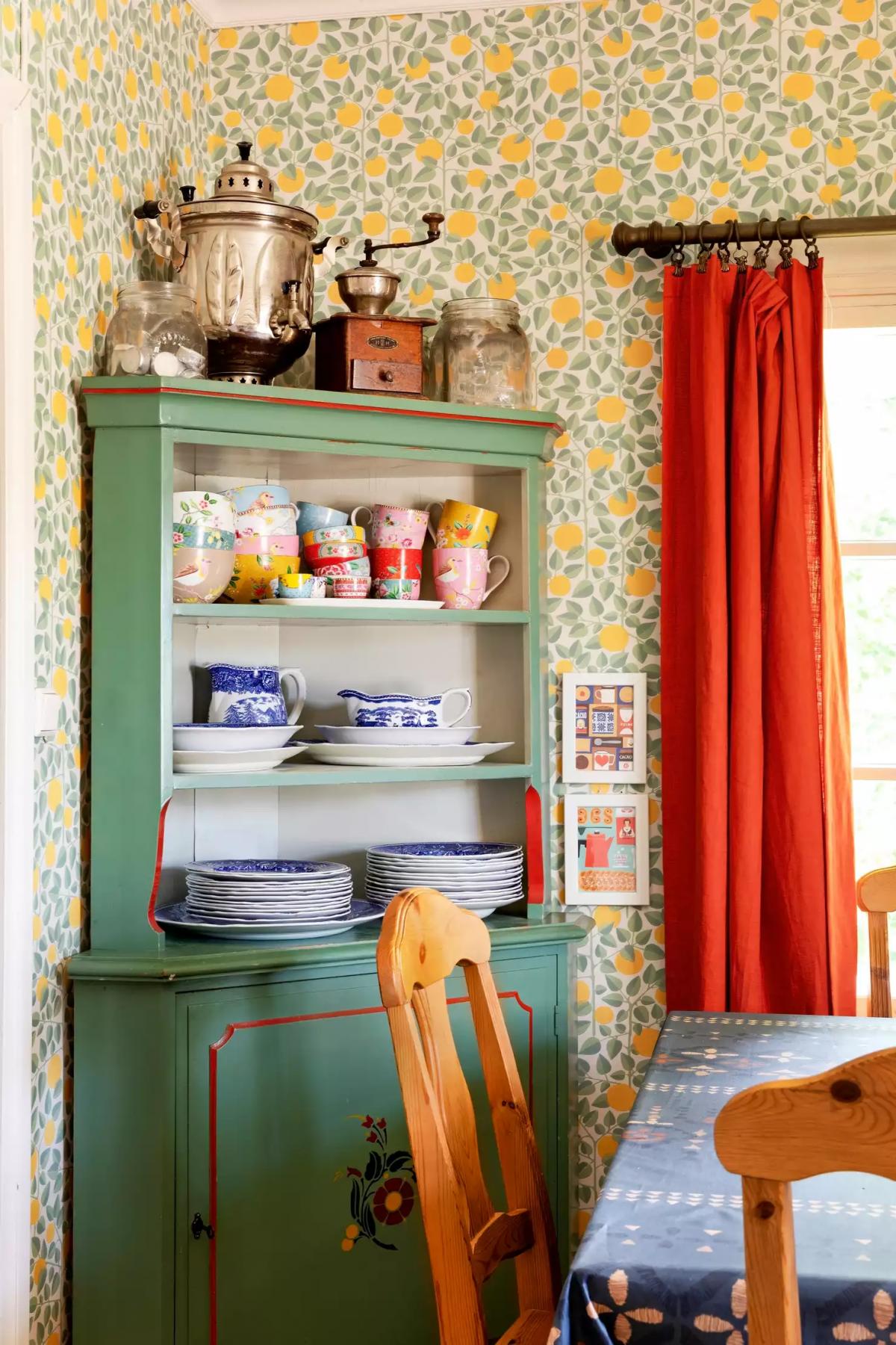 Old green cupboard with a collection of mugs and plates