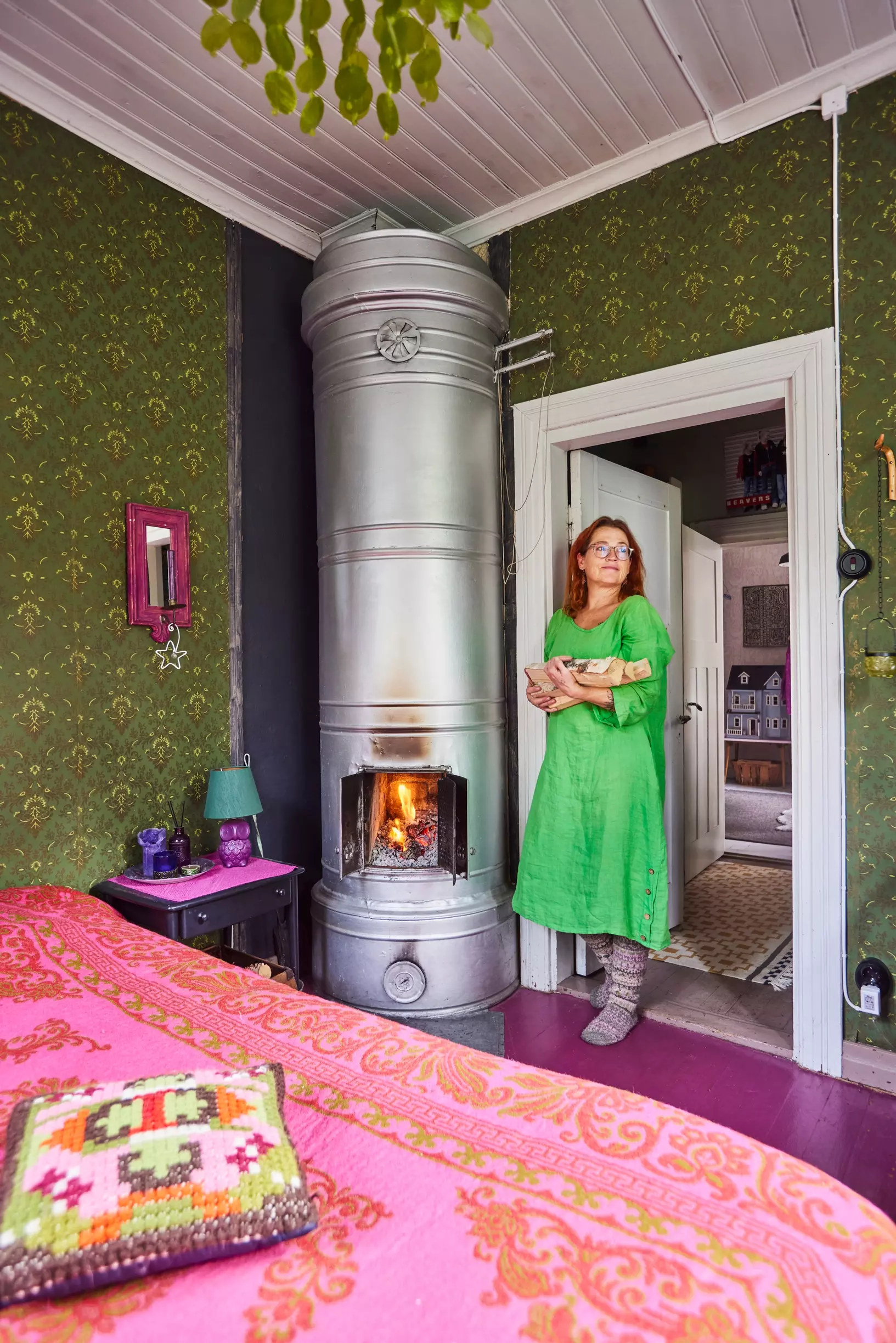 Guest bedroom in a Finnish home with dark green walls and a raspberry-colored floor