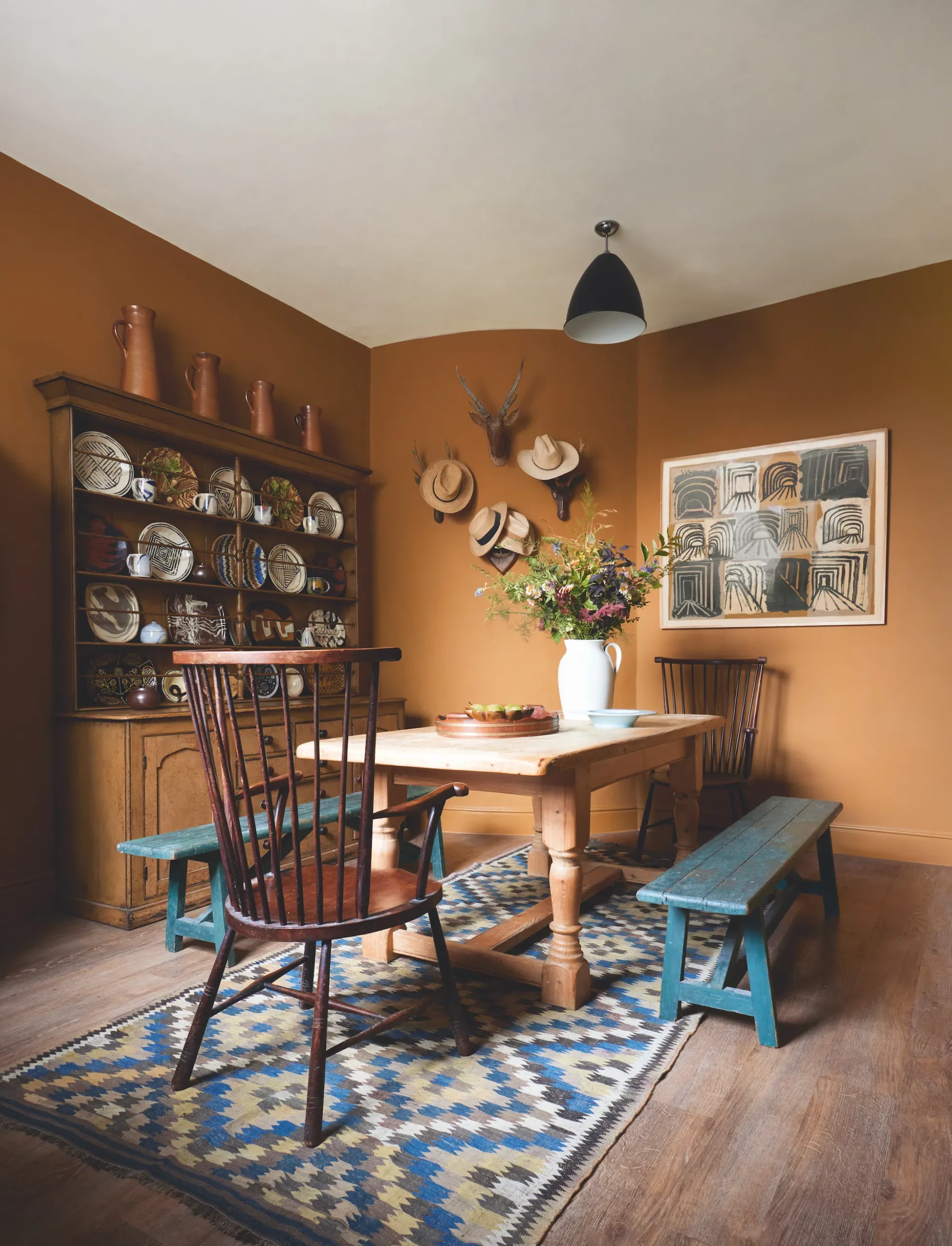 Brown dining area with vintage benches and a collection of ceramic dishes